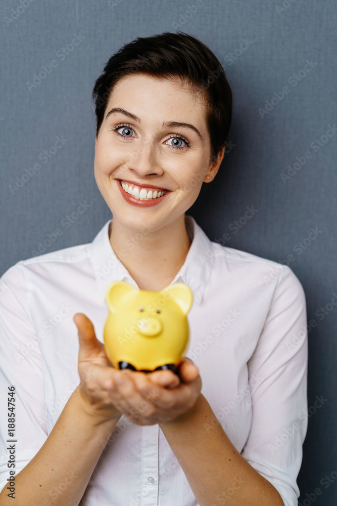 Young smiling woman with yellow piggy bank