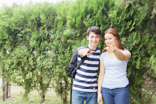Couple of teenagers happy outdoor pointing their fingers
