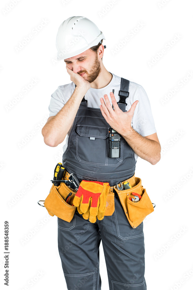 A builder or employee in a protective helmet holds a handle near the cheek and suffers from toothache. Isolated over white background. A builder or employee in a protective helmet holds a handle near the cheek and suffers from toothache. Isolated over white background.
