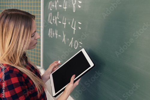 Female maths teacher writing equations on a board photo