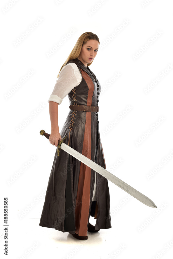 full length portrait of girl wearing brown fantasy costume, holding a sword. standing pose on white studio background. full length portrait of girl wearing brown fantasy costume, holding a sword. standing pose on white studio background.