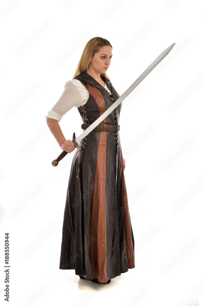 full length portrait of girl wearing brown fantasy costume, holding a sword. standing pose on white studio background. full length portrait of girl wearing brown fantasy costume, holding a sword. standing pose on white studio background.