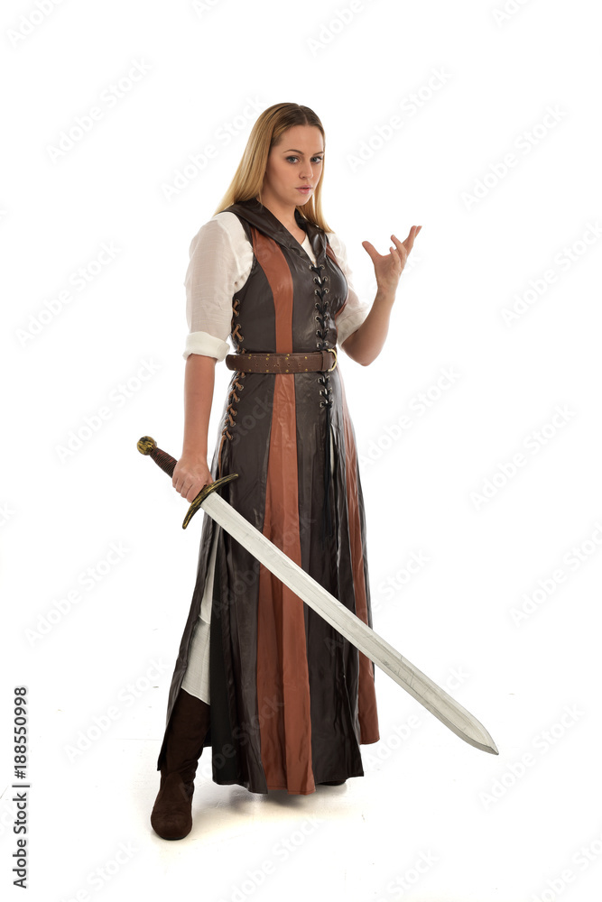 full length portrait of girl wearing brown fantasy costume, holding a sword. standing pose on white studio background. full length portrait of girl wearing brown fantasy costume, holding a sword. standing pose on white studio background.