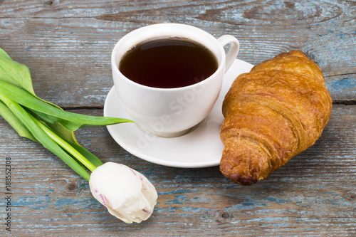 tulips and coffee cup and croissant on wooden table. Top view with copy space photo