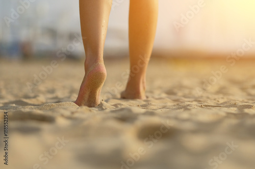 barefoot girl walking on the sand beach with sunset light