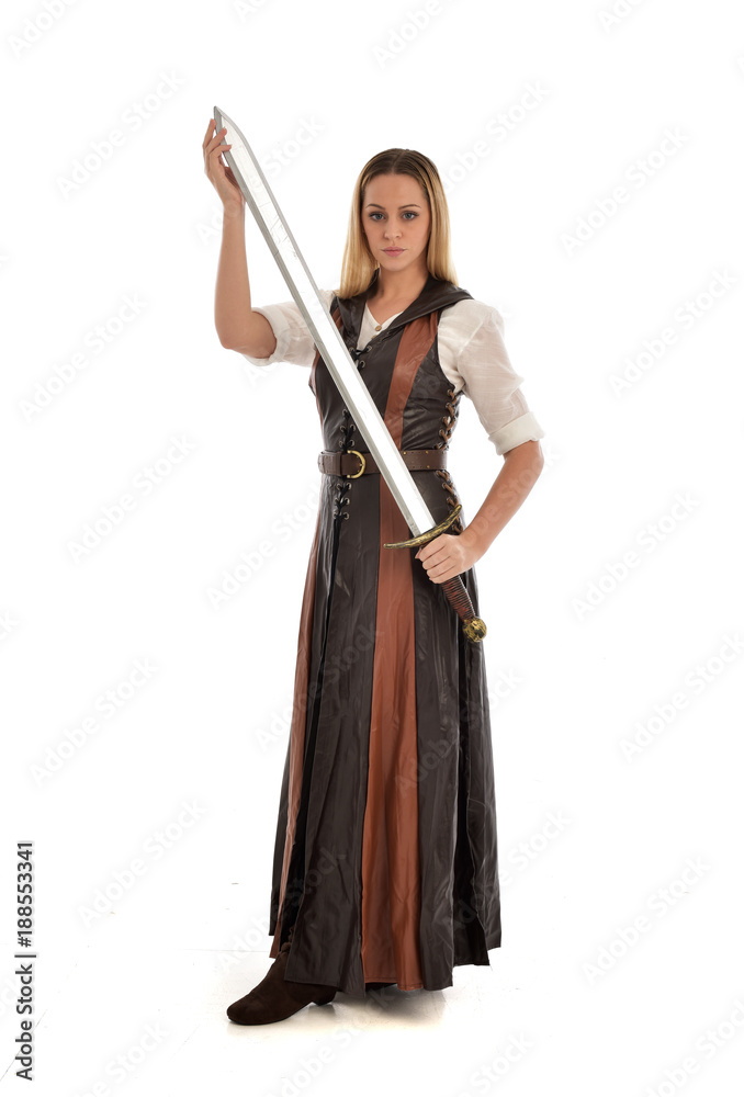 full length portrait of girl wearing brown  fantasy costume, holding a sword. standing pose on white studio background. 