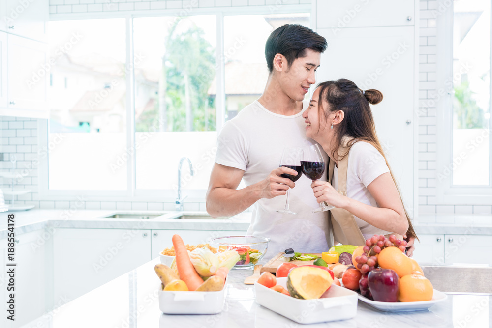 Asian lovers or couples drinking wine in kitchen room at home. Love and happiness concept Sweet honeymoon and Valentine day theme