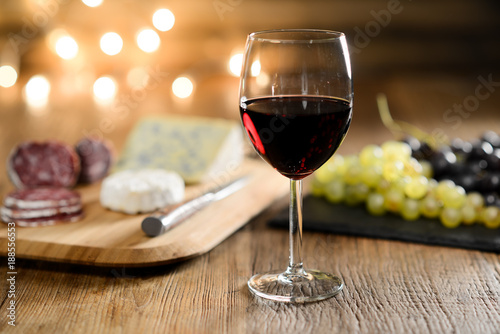 glass of red wine with french cheese and delicatessen in restaurant wooden table with romantic dim light and cosy atmosphere