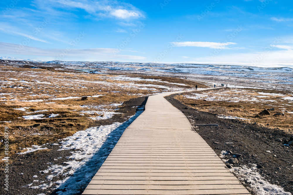 Walkway of gullfoss waterfall in Iceland surrounding by grass field with blue sky