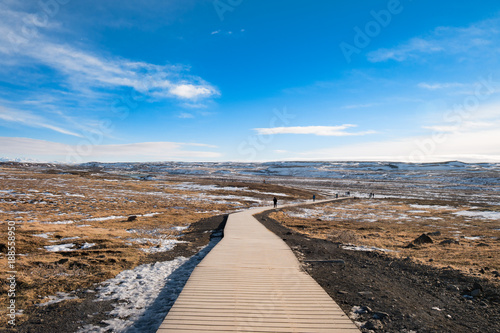 Walkway of gullfoss waterfall in Iceland surrounding by grass field with blue sky