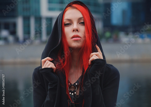 pretty slim red haired alternative girl walking in the city park alone