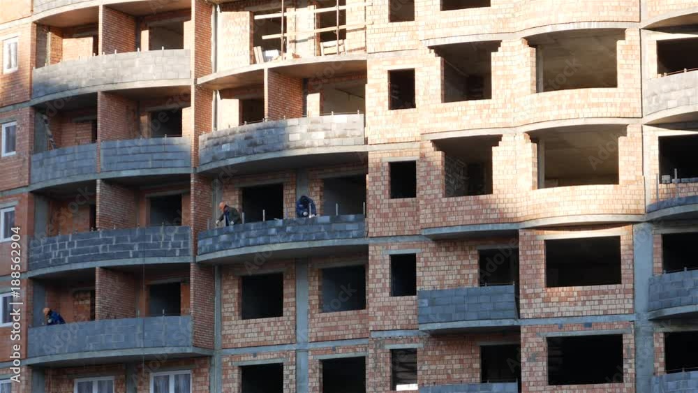 workers builders installers and welders are working in a brick building under construction. sunny day workers builders installers and welders are working in a brick building under construction. sunny day