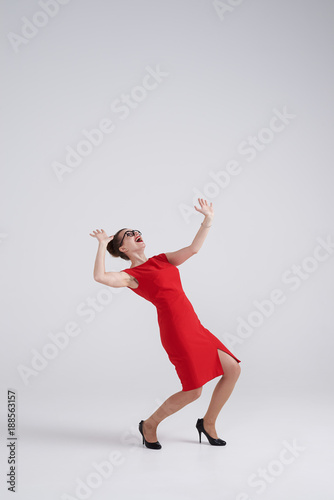 Scared woman in red dress getting crushed by an invisible object above