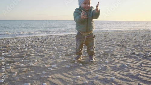 Lifestyle of the baby. A boy is played with sand and stones on a natural beach. shot with stedicam