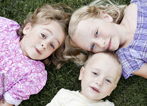 Two girls and boy lying on grass