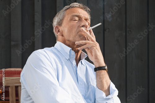 Senior man wearing shirt smoking cigarette