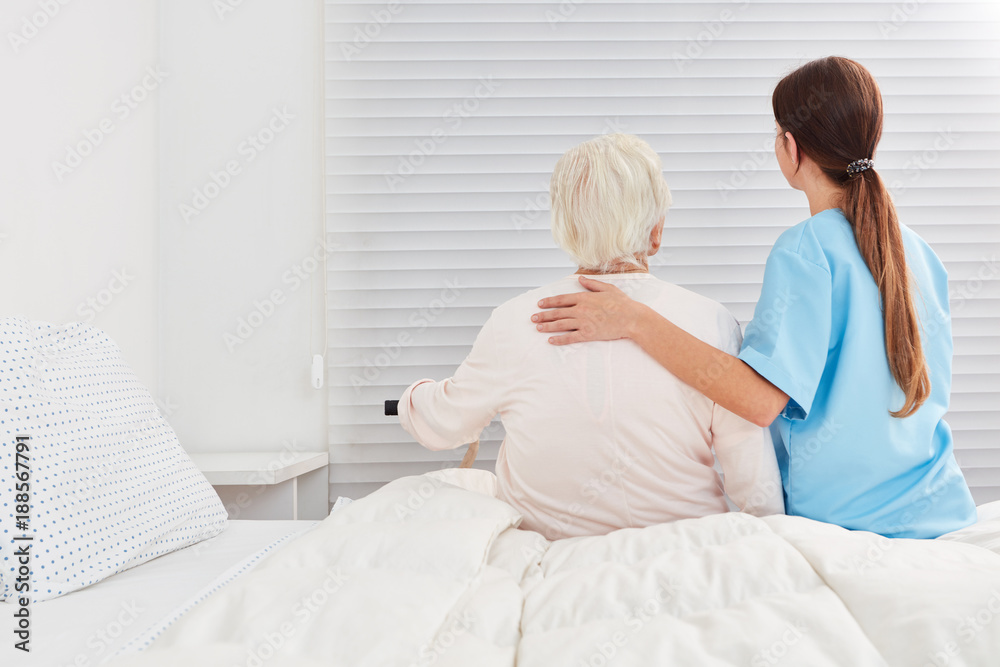 Pflegerin hilft Seniorin aus dem Bett in der Reha - obrazy, fototapety, plakaty 