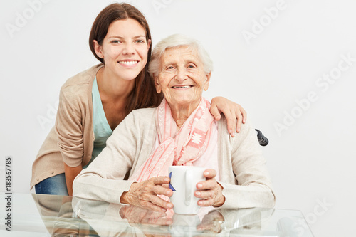 Junge Frau als Altenpfleger betreut eine Seniorin photo