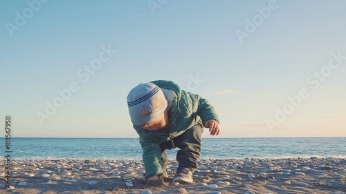 Lifestyle of the one year old baby. A boy is played with sand and stones on a natural beach. shot with stedicam
