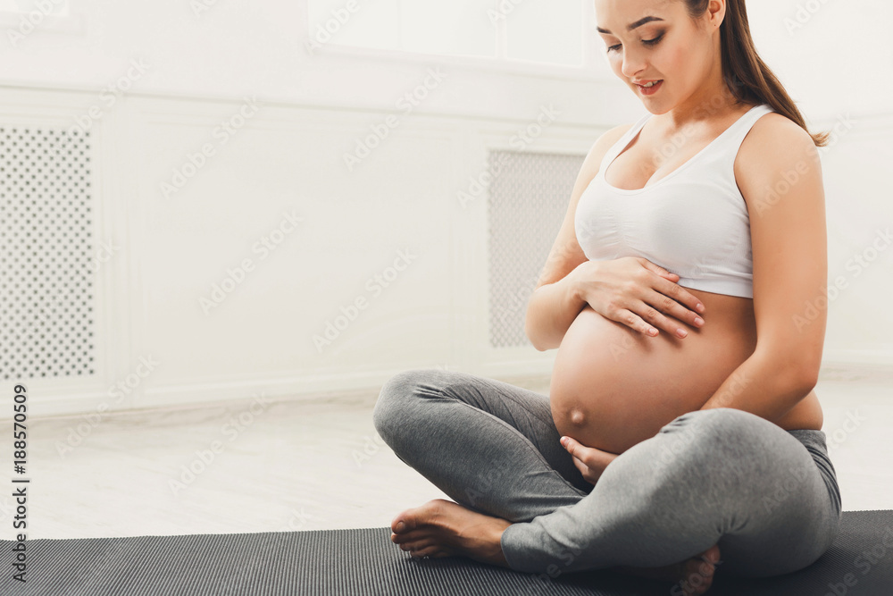 Pregnant woman caressing her belly at home