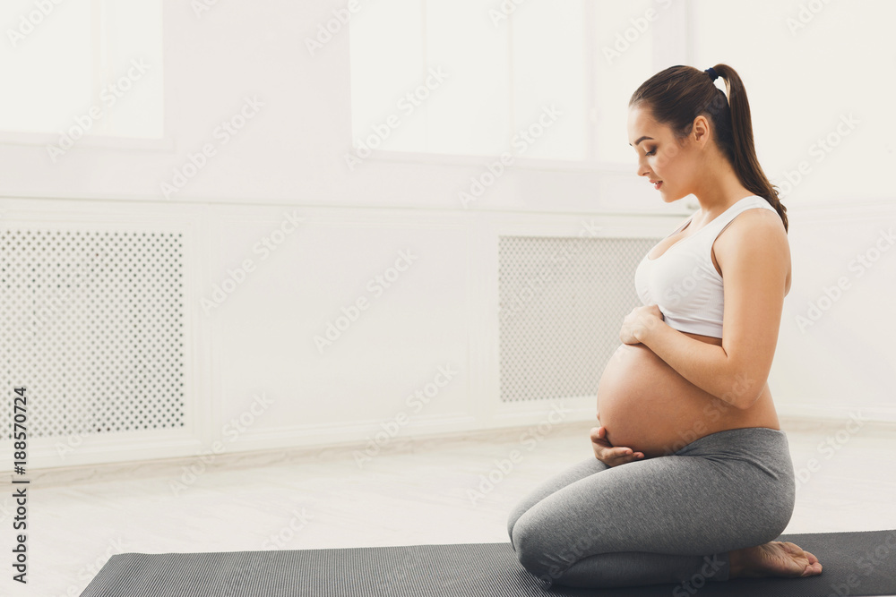 Pregnant woman training yoga in lotus pose Pregnant woman training yoga in lotus pose