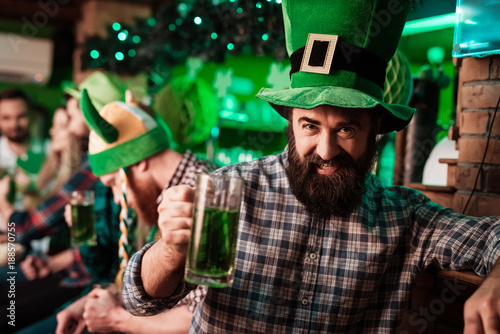 The guy in the cap of the leprechaun is drinking beer.