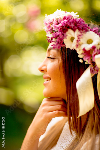 Portrait of young woman with wreath of fresh flowers on head