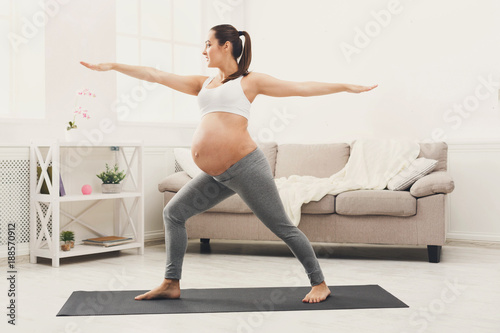 Happy pregnant woman training yoga in hero pose © Prostock-studio