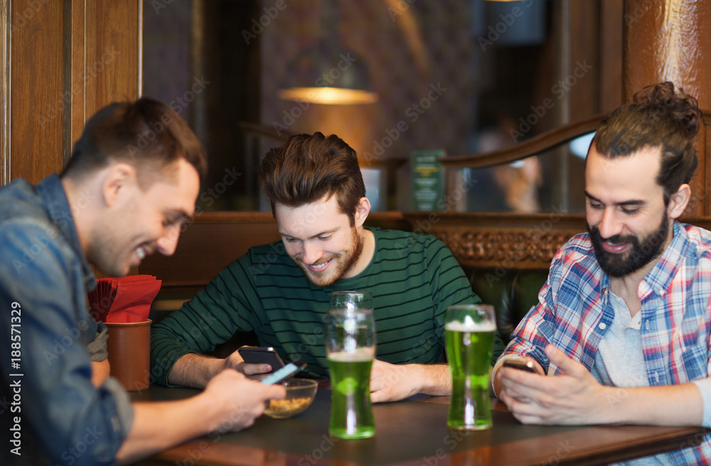 friends with smartphones and green beer at pub friends with smartphones and green beer at pub