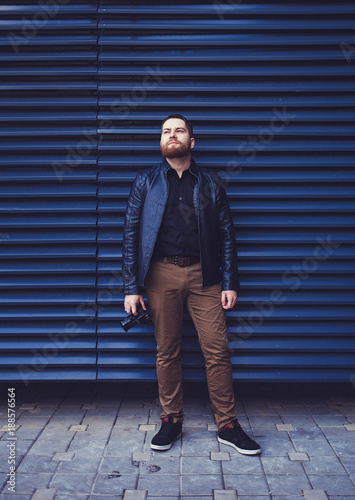 Young man wearing a leather jacket against a blue wall