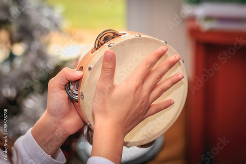 Schilderij op canvas girl plays the tambourine in front of a Christmas tree