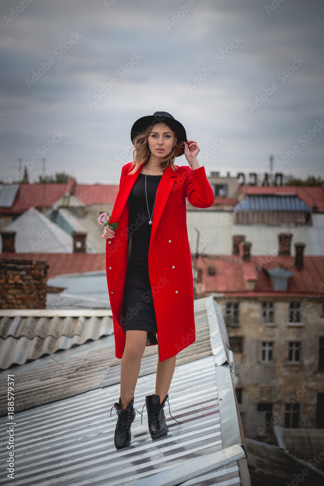 Fototapeta premium Girl in red posing on the roof of old city