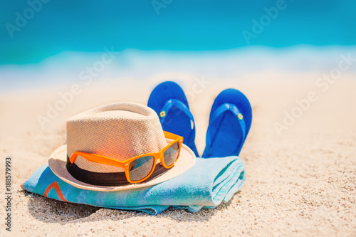 Sandy beach with towel, hat and summer accessories with copy space. Vacation and travel items. Tropical Holiday Background