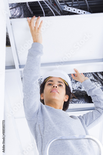 female worker repairs gypsum plasterboard frame with spackling paste