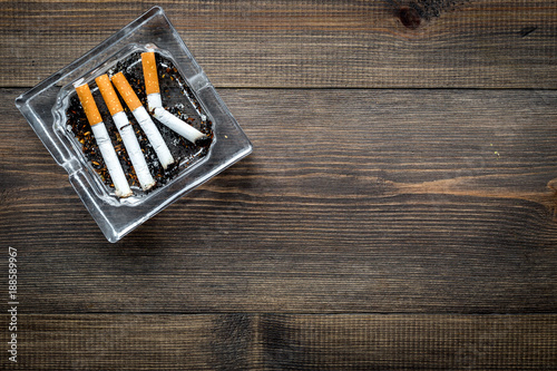 Smoking. Half-smoked cigarettes in ashtray on dark wooden background top view copy space