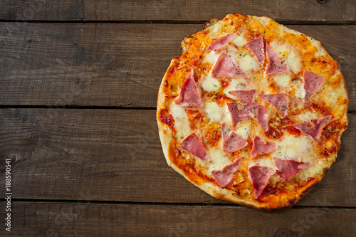 home made ham pizza on wooden surface