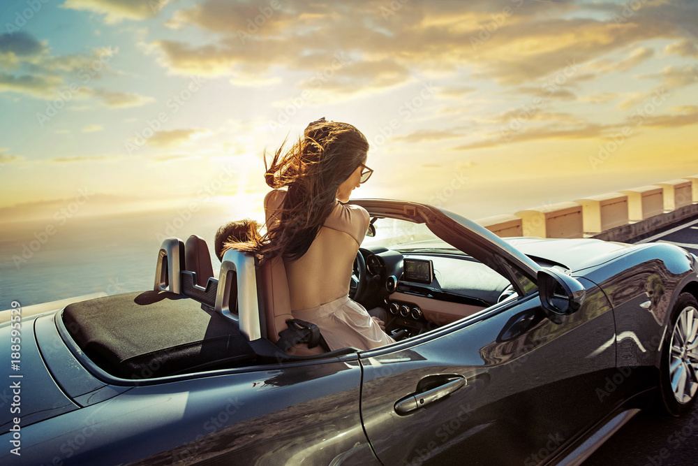 Relaxed couple riding a convertible - obrazy, fototapety, plakaty 