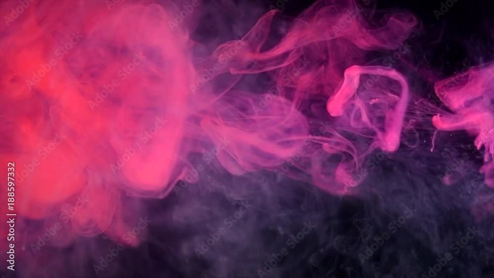 Abstract red neon flowing ink in water over black background. Dropping colorful ink into the water. Slow motion 4K UHD video footage. 3840X2160