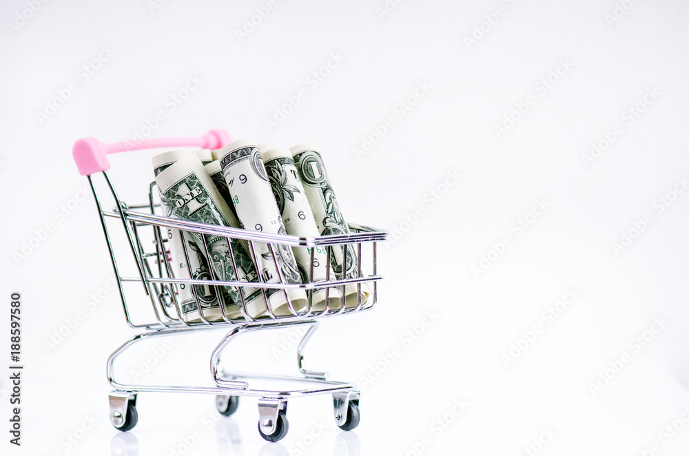 Full shopping trolley with dollar banknotes on a white background. Isolated. Concept of consumerism and money. 