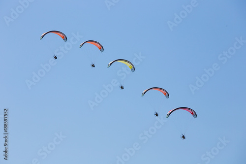 Paratroopers Air show - powered parachutes in the line, during aircraft exhibition with trail of italian flag colors over Grado beach, Italy.