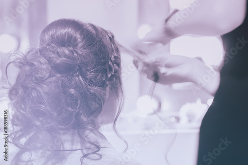 Unrecognizable girl back to us, girl in mirror at hairdresser making hairstyle, styling from long hair, hair salon, partially visible hands master. Blurred, toned