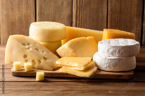 Various types of cheese on dark rustic wooden background.