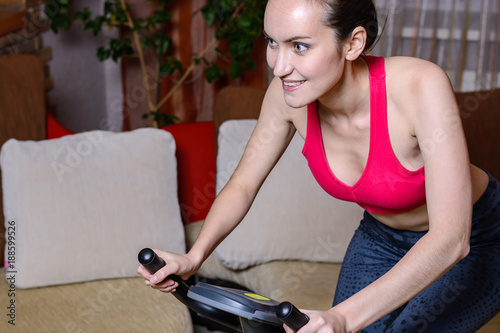 Portrait of happy young woman on exercise bike. The concept of home fitness