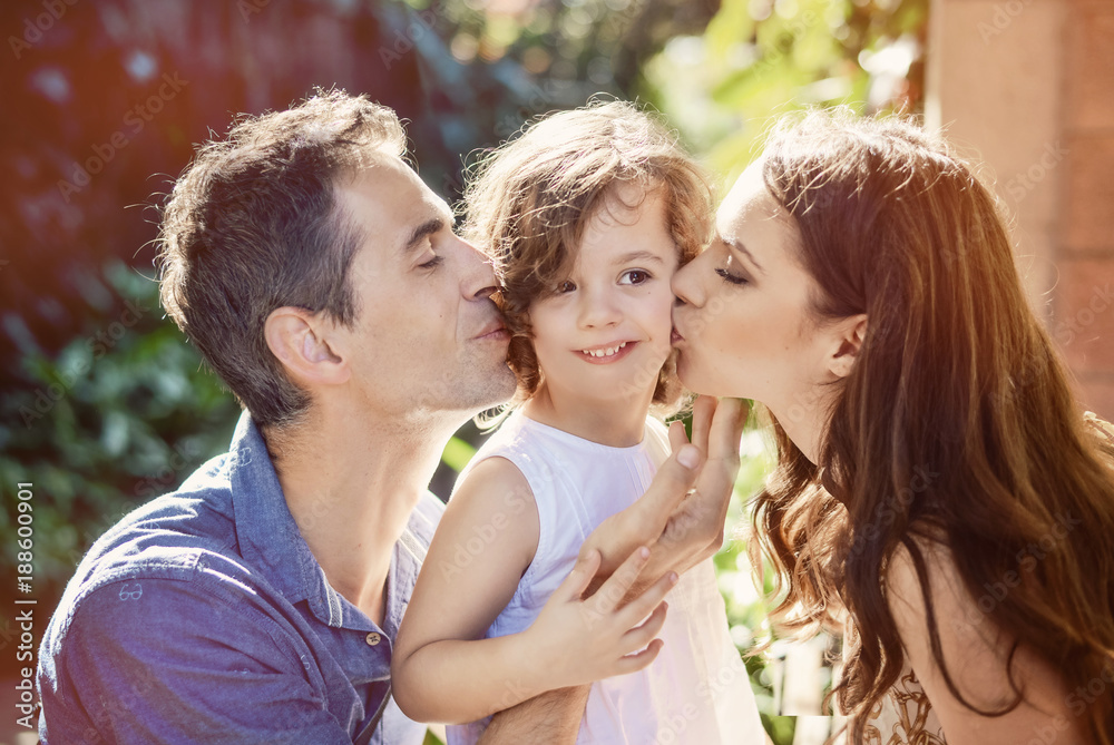 Happy parents kissing their beloved child Happy parents kissing their beloved child