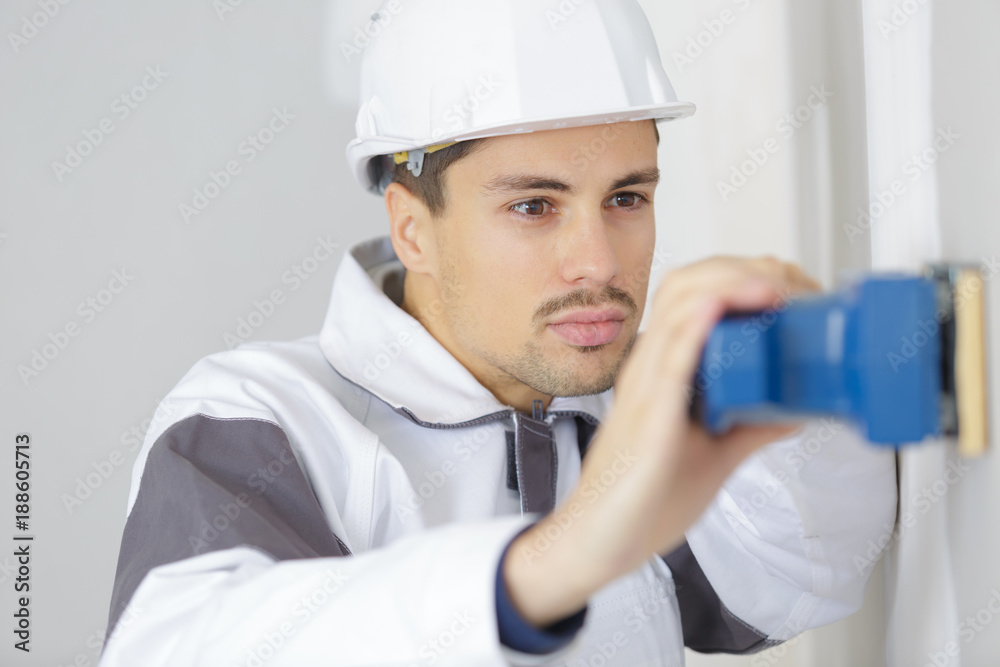 male builder sanding wall indoors male builder sanding wall indoors