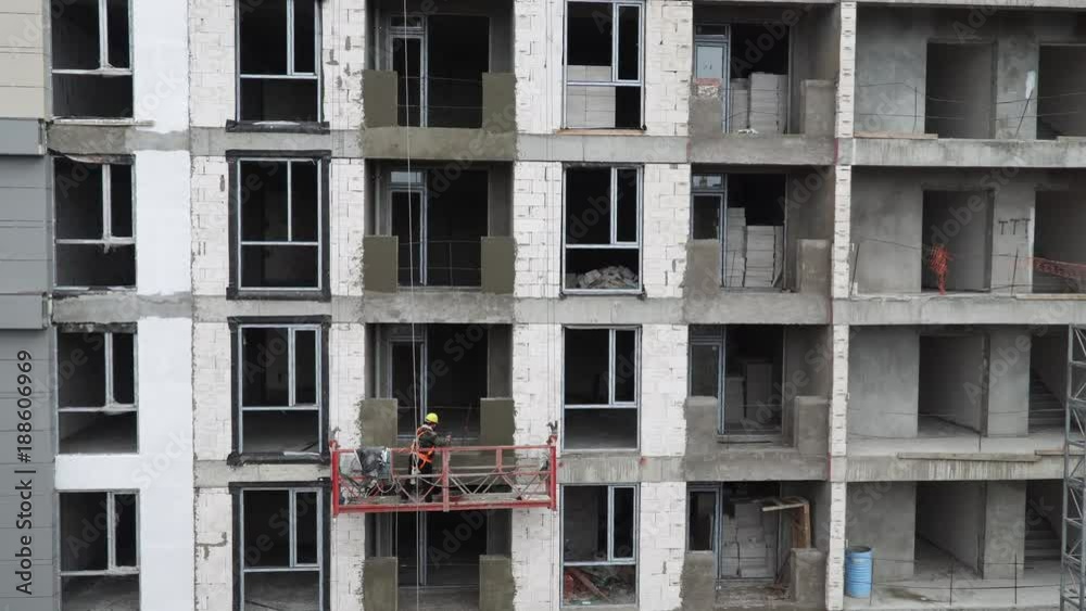 workers work on building a building in a hanging cradle workers work on building a building in a hanging cradle