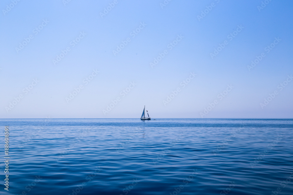 Fototapeta premium A Sail boat on the horizon at dusk in the Mediterranean Sea