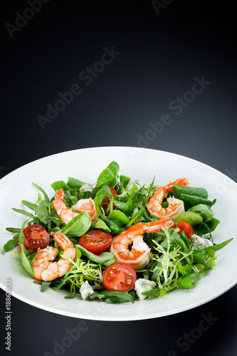 Shrimp salad with arugula, cherry tomato and blue cheese, vertical close up shot on the dark background