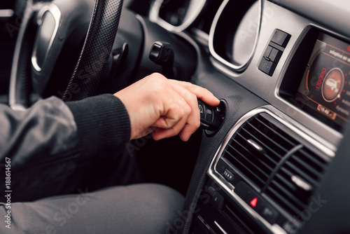 Businessman starts his stylish modern car with the key. Close up man's hand with the key.
