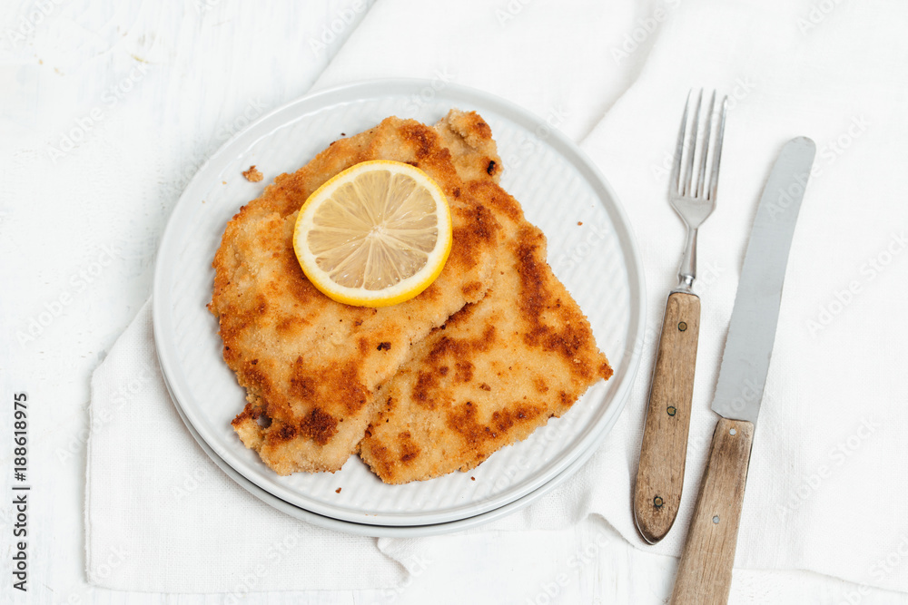 Traditional German or Austrian Wiener Schnitzel or Schnitzel Wiener Art made of breaded and pan-fried butterfly cutlet of pork, veal of chicken meat served with a slice of lemon